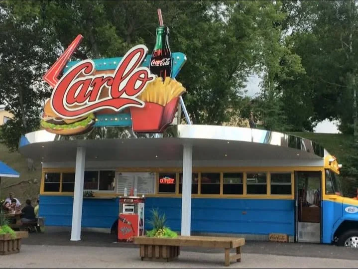 Le vieil autobus bleu et jaune de La Patate à Carlo sous son enseigne rouge « Carlo »